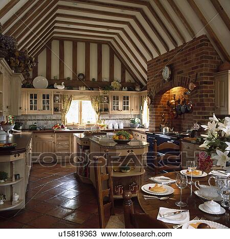 Large neutral kitchen in converted barn with terracotta floor and dining table set for lunch View Large Photo Image Stock Image - Large neutral kitchen in converted barn with terracotta floor and dining table set for lunch. Fotosearch