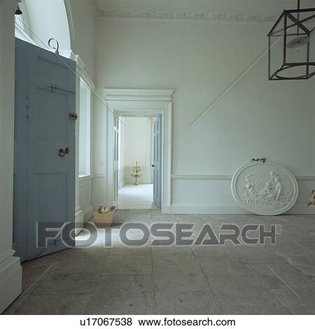 Stock Photo - Large oval plaster plaque on stone tiled floor in large white Georgian hall with pastel blue door. Fotosearch