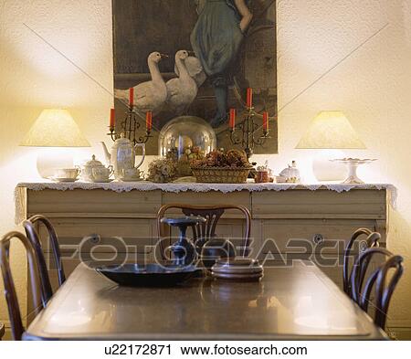 Large Picture Above Sideboard With Lighted Lamps And Glass