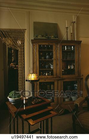 Stock Image - Lighted Art Nouveau lamp on nest-of-tables. Fotosearch