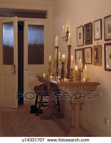 Lighted candles in tall candlesticks on wooden console table in hall with engraved glass panels in double doors View Large Photo Image Stock Photo - Lighted candles in tall candlesticks on wooden console table in hall with engraved glass panels in double doors. Fotosearch