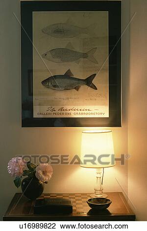 Stock Image - Lighted lamp below fish picture. Fotosearch