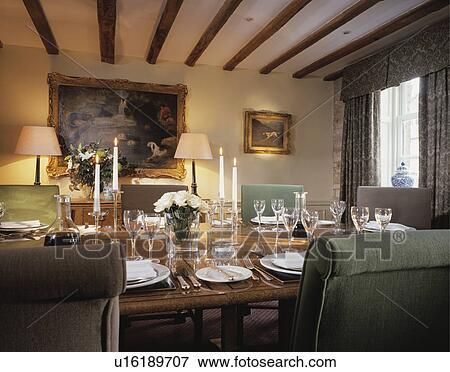 Stock Photo - Lighted lamps and candles in beamed hotel dining room with polished table. Fotosearch