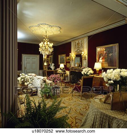 Stock Image - Lighted lamps and chandelier in country drawing room. Fotosearch