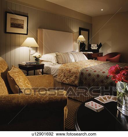 Lighted lamps on either side of bed with patterned bed covers in hotel bedroom View Large Photo Image Stock Image - Lighted lamps on either side of bed with patterned bed covers in hotel bedroom. Fotosearch