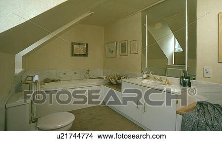 Picture - Lighted mirror above basin in vanity unit in attic bathroom. Fotosearch