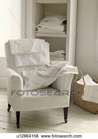 Linen sheets and pillow on armchair with white loosecover View Large Photo Image Stock Photo - Linen sheets and pillow on armchair with white loosecover. Fotosearch