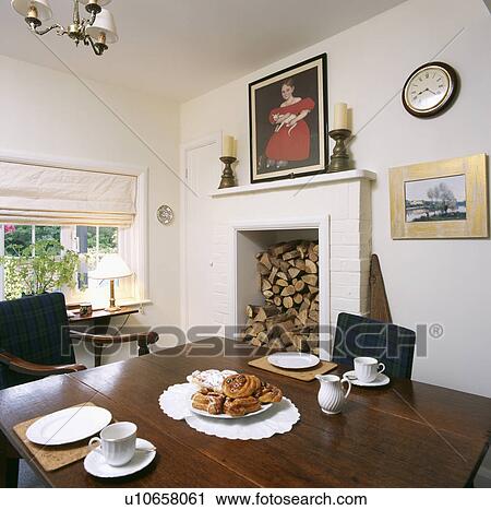 Logs stored in fireplace in small white dining room with table set for tea View Large Photo Image Stock Image - Logs stored in fireplace in small white dining room with table set for tea. Fotosearch