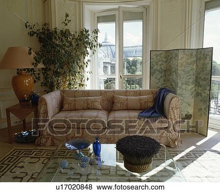 Stock Photo - Loosecover on sofa in traditional living room with screen in front of window. Fotosearch
