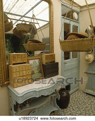 Picture - Miniature chests of drawers on marble-topped pastel blue Edwardian cupboard below mirror in small hall. Fotosearch