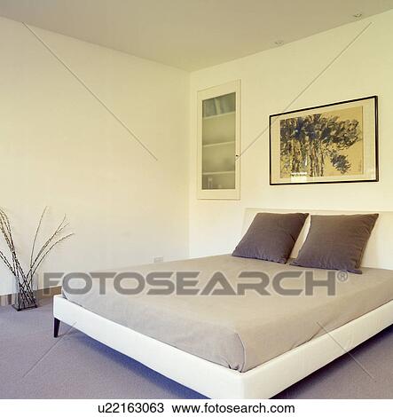 Stock Image - Minimalist bedoorm with brown cushions on modern bed. Fotosearch