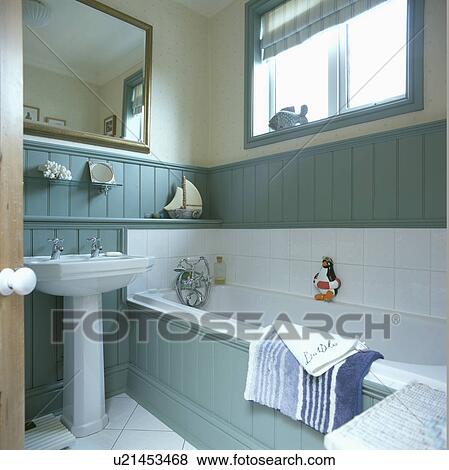 Stock Photo - Mirror above white pedestal basin in turquoise panelled bathroom . Fotosearch