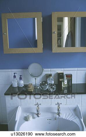 Stock Image - Mirrored double cabinets above traditional basin set into modern granite topped bathroom vanity unit. Fotosearch