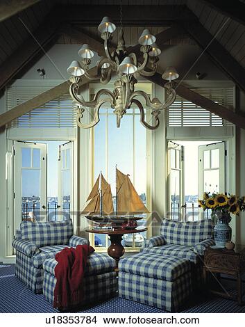 Model boat between blue+white armchairs in coastal living room with view of the sea View Large Photo Image Picture - Model boat between blue+white armchairs in coastal living room with view of the sea. Fotosearch