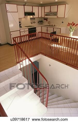 Modern white kitchen with wooden flooring on landing above staircase with white floor tiles View Large Photo Image Stock Photo - Modern white kitchen with wooden flooring on landing above staircase with white floor tiles. Fotosearch