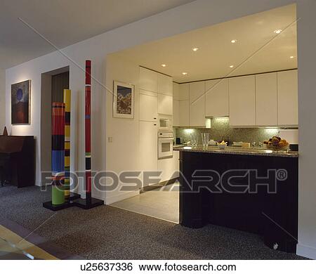 Multi-coloured striped pillar sculpture in modern white kitchen with recessed lighting and black island unit View Large Photo Image Stock Photograph - Multi-coloured striped pillar sculpture in modern white kitchen with recessed lighting and black island unit. Fotosearch