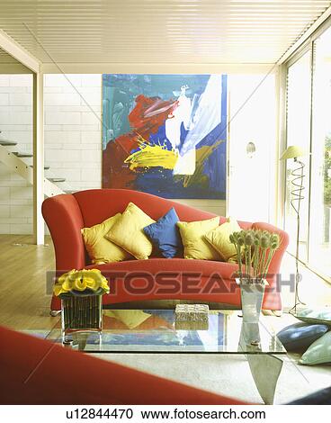 Stock Image - Multicoloured cushions on red sofa in modern living room. Fotosearch