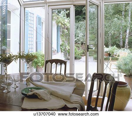 Napkins and glasses on table in conservatory dining room with view of garden through patio doors View Large Photo Image Stock Image - Napkins and glasses on table in conservatory dining room with view of garden through patio doors. Fotosearch