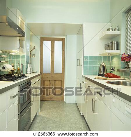Narrow modern town kitchen with white units and turquoise wall tiles View Large Photo Image Stock Photograph - Narrow modern town kitchen with white units and turquoise wall tiles. Fotosearch