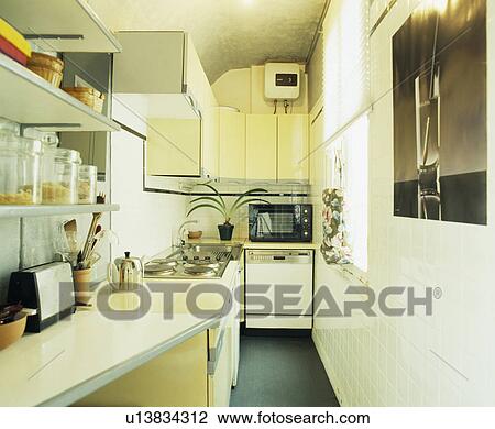 Stock Image - Narrow white economy-style galley kitchen with microwave above dishwasher. Fotosearch