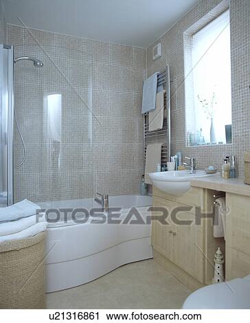Stock Image - Natural coloured modern bathroom with curved bath. Fotosearch