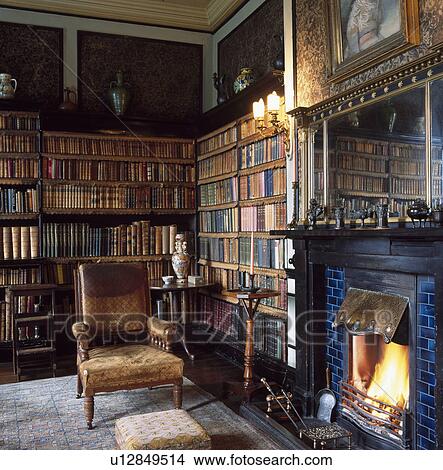 Old Leather Armchair Beside Fireplace With Lighted Fire In Country
