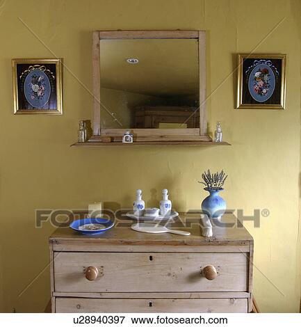 Old Pine Mirror Above Old Pine Chest Of Drawers In Pastel Yellow