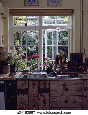 Stock Photo - Open casement window above stainless steel sink in reclaimed rustic wood fitted cupboards. Fotosearch