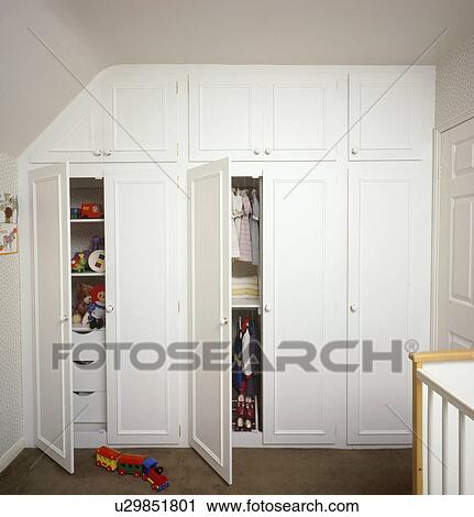 Open Doors On Fitted Storage Cupboards In Childs White Bedroom