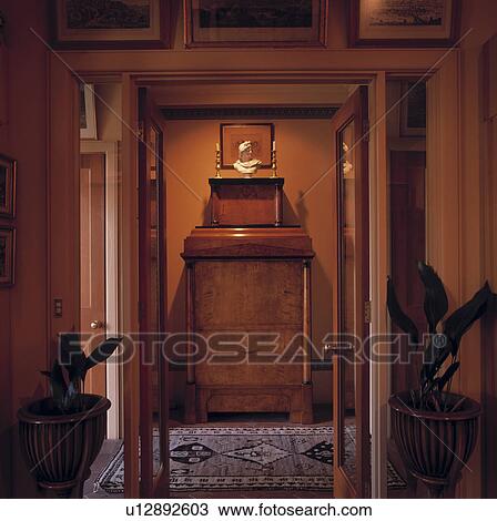 Stock Image - Open double doors to hall with classical bust on antique walnut cupboard. Fotosearch