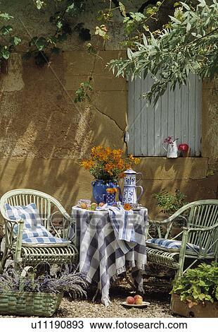 Stock Image - Orange flowers and blue cloth on table in country garden in summer. Fotosearch