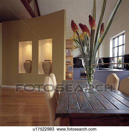Orange flowers in vase on rectangular wooden table in modern dining room with terracotta pots in lighted alcoves View Large Photo Image Stock Image - Orange flowers in vase on rectangular wooden table in modern dining room with terracotta pots in lighted alcoves. Fotosearch