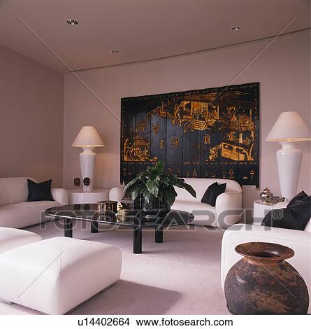 Oriental screen on wall of modern living room with white sofas and lighted lamps View Large Photo Image Picture - Oriental screen on wall of modern living room with white sofas and lighted lamps. Fotosearch