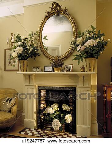 Oval Gilt Mirror Above Fl Arrangements On Cream Fireplace Gilt Mirror Above Fl Arrangements