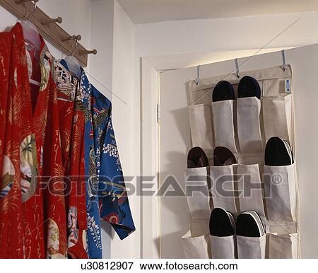 Stock Photo - Over-door shoe storage beside Oriental-style robes hung on a wooden coat peg in a modern bedroom . Fotosearch