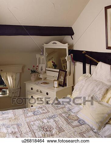 Painted Cream Dressing Table Beside Bed With Patterned Quilt And Pale Yellow Cushions In Cream Attic Bedroom Picture U26818464 Fotosearch