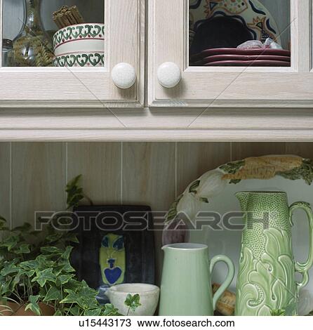 Stock Image - Pale green jugs on worktop below kitchen cupboard. Fotosearch