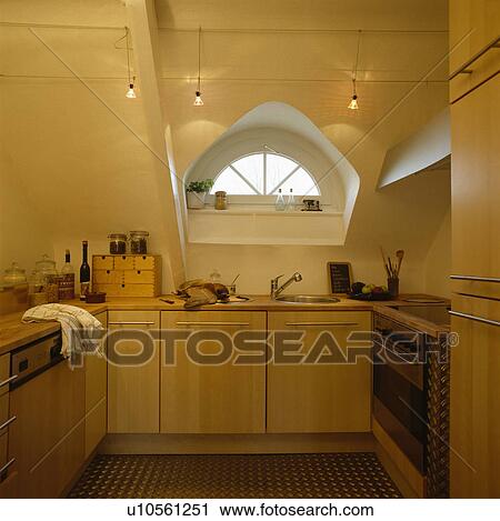 Pale Wood Fitted Cupboards Below Small Dormer Window In Modern