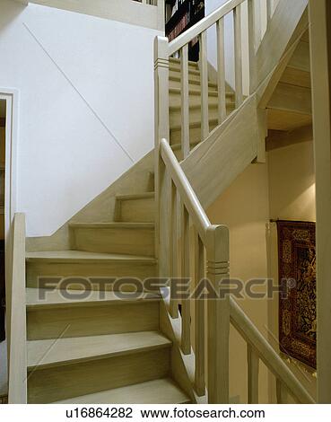 Stock Image - Pale wood staircase in neutral hall. Fotosearch