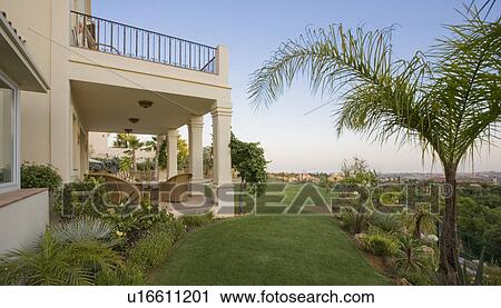 Palm tree and lawn in garden of Spanish villa with wicker furniture on veranda View Large Photo Image Stock Image - Palm tree and lawn in garden of Spanish villa with wicker furniture on veranda. Fotosearch