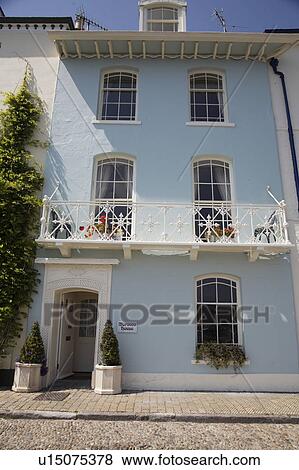 Stock Photo - Pastel blue Georgian townhouse with white wrought-iron balcony and shrubs in white pots on either side of door. Fotosearch