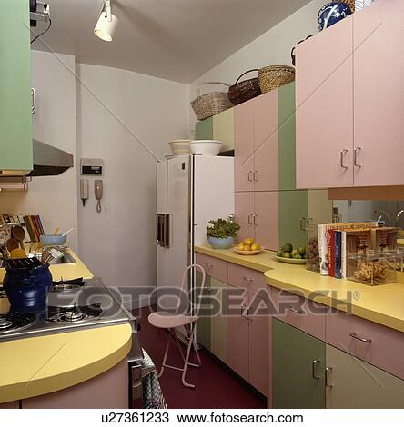 Stock Image - Pastel pink and green kitchen with large American style fridge freezer. Fotosearch