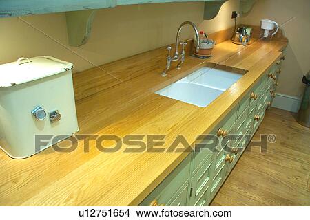 Picture - Pastel turquoise kitchen unit with enamel breadbin on wood worktop with underset double ceramic sinks. Fotosearch
