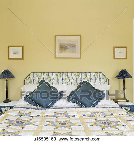 Patchwork quilt and blue cushions on bed with upholstered headboard with yellow bedroom with blue lamps View Large Photo Image Stock Image - Patchwork quilt and blue cushions on bed with upholstered headboard with yellow bedroom with blue lamps. Fotosearch