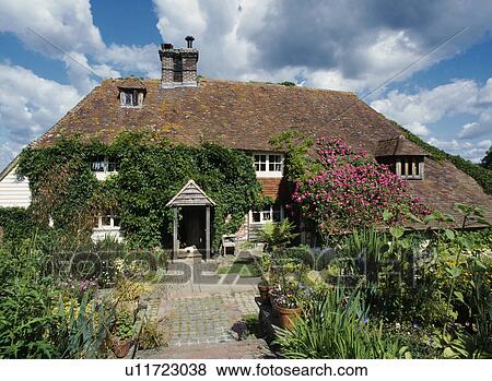 Stock Photo - Path through summer garden to traditional ivy-clad country cottage. Fotosearch
