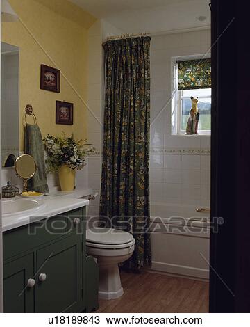 Patterned green curtain beside bath in pastel yellow bathroom with fitted green vanity unit View Large Photo Image Stock Image - Patterned green curtain beside bath in pastel yellow bathroom with fitted green vanity unit. Fotosearch