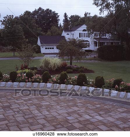 Paved and curved patio with stone edging with white house in background in early evening View Large Photo Image Stock Photo - Paved and curved patio with stone edging with white house in background in early evening. Fotosearch