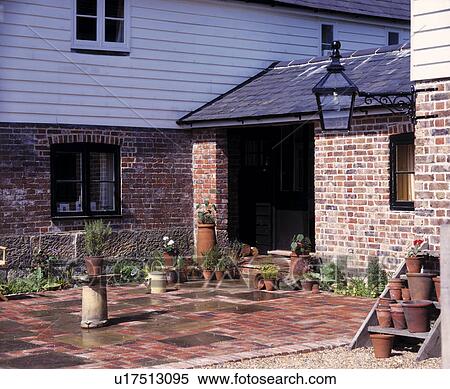 Stock Photography - Paved patio in front of traditional clapboard and brick cottage with brick extension. Fotosearch