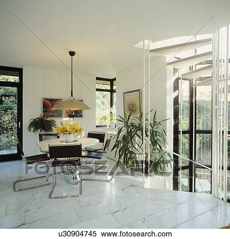 Pendant Light Over White Circular Table And Black Leather And