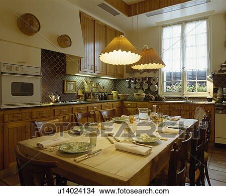Pendant lights above place settings on pine table in traditional kitchen View Large Photo Image Picture - Pendant lights above place settings on pine table in traditional kitchen. Fotosearch